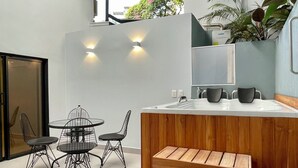 A modern kitchen with a wooden island, two black wire chairs, a round table, and a built-in sink. - Lalinde by Wynwood House (Medellín)
