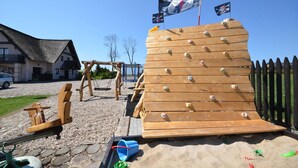 Eine hölzerne Kletterkonstruktion mit einer Flagge, einer Schaukel und einem Sandkasten.