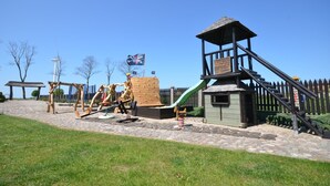 Ein Spielplatz mit Schaukeln, einer Rutsche und einer Kletterkonstruktion.