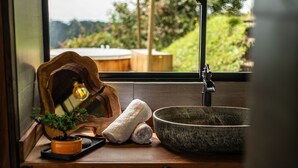 A wooden countertop with a potted plant, a rolled towel, and a large bowl. - Owl's Watch Nature Retreat (Manizales)