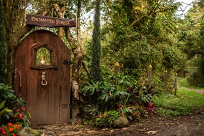 Una puerta de madera con un letrero que dice "Enchanted Forest" y una pequeña figurita de hada.