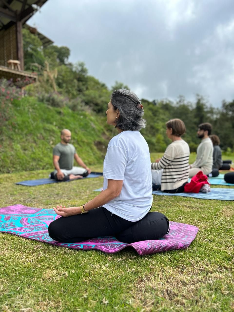 Un grupo de personas sentadas sobre esterillas de yoga en el césped.