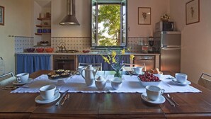 A dining area with a wooden table set for breakfast, a stove, and a window with a view of trees. - Tuscan Holiday Home with Pool (Chiusi)