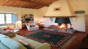 A cozy living room with a fireplace, wooden beams, a sofa, and a patterned rug. - Tuscan Holiday Home with Pool (Chiusi)