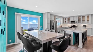 A modern kitchen with white cabinets, a central island with seating, and a view of the sea through large windows. - Lighthouse Retreat Close to Lambeau Field
and the amazingDoor county Fall Color (Algoma)