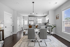 A modern kitchen with white cabinets, a central island, and pendant lighting. - Downtown RVA Cozy 3BR Near VCU (Richmond)