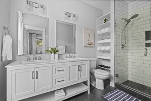 A modern bathroom with a double sink vanity, a glass shower enclosure, and a toilet. - Downtown RVA Cozy 3BR Near VCU (Richmond)