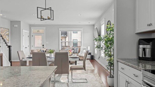 A modern kitchen with a marble countertop, a coffee machine, and a dining area with a table and chairs. - Spacious Duplex, Near VCU, 5 Free Parking, Fenced (Richmond)
