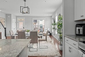 A modern kitchen with a marble countertop, a coffee machine, and a dining area with a table and chairs. - Spacious Duplex, Near VCU, 5 Free Parking, Fenced (Richmond)