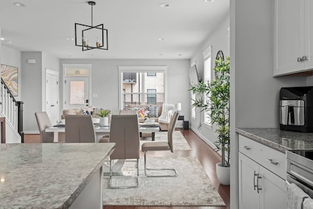A modern kitchen with a marble countertop, a coffee machine, and a dining area with a table and chairs.