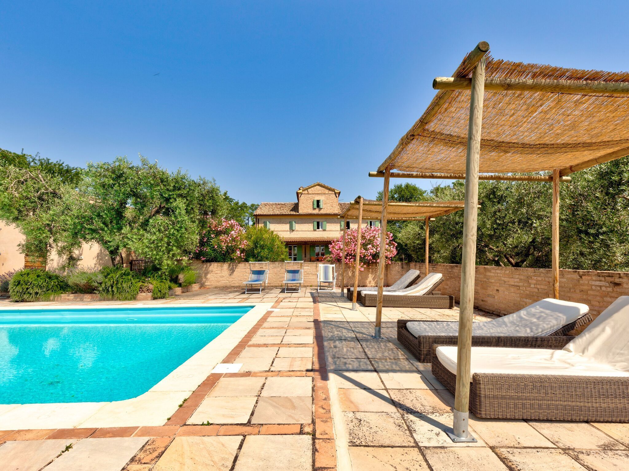 A pool area with lounge chairs and a pergola.