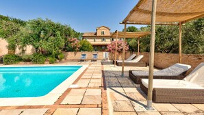 Un área de piscina con sillones de descanso y una pérgola.