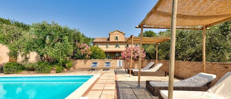 Uma área de piscina com espreguiçadeiras e um pérgola.