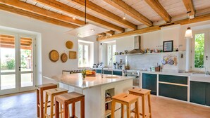 Una cocina amplia con una isla grande, taburetes de madera y un techo alto con vigas a la vista.