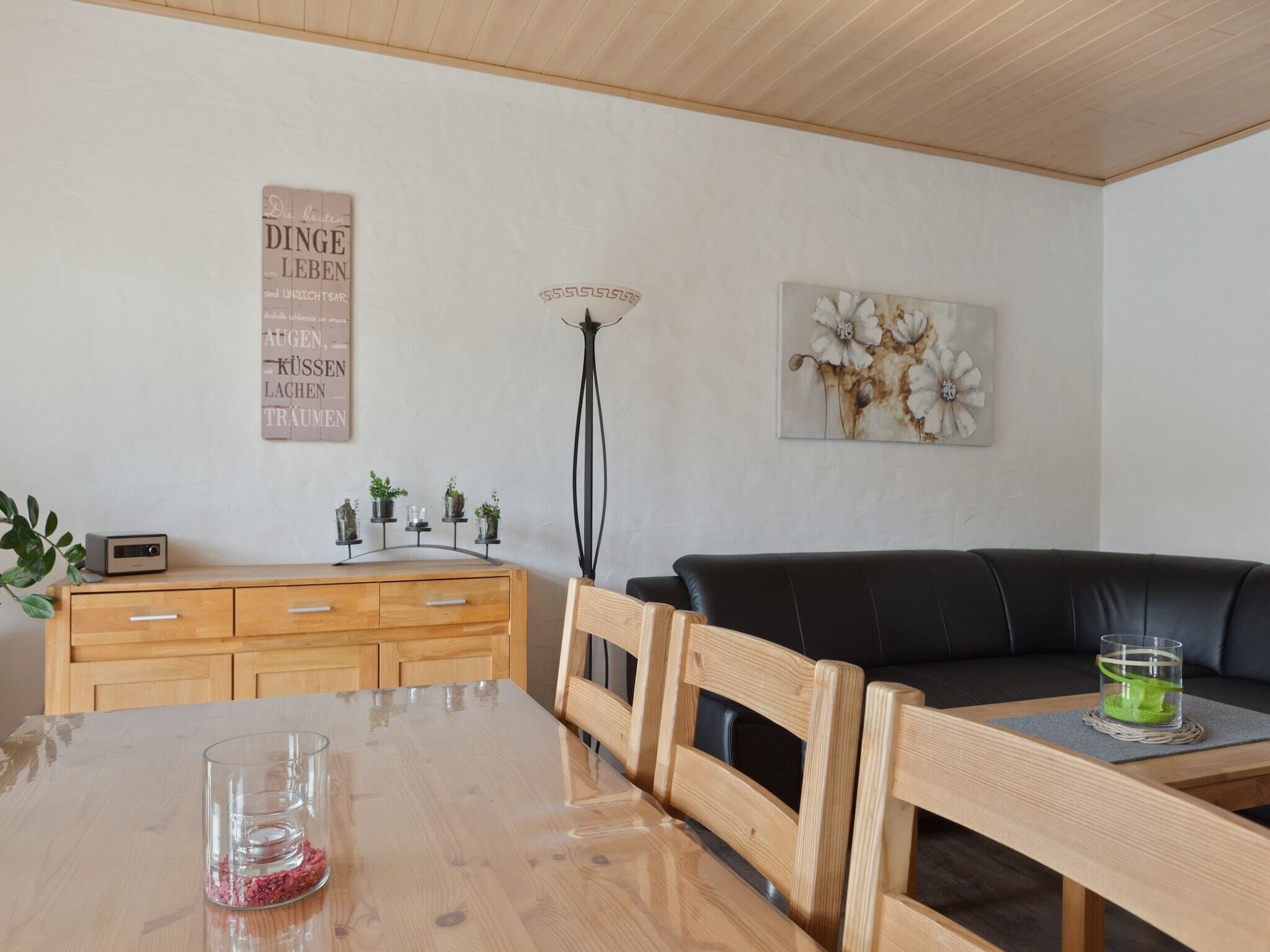 Un salon moderne avec une table à manger en bois, un canapé en cuir noir et une décoration minimaliste.