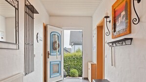 A hallway with a blue-framed door, a bench, a radiator, a wall-mounted light fixture, and a framed picture.