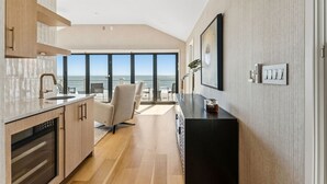 Une cuisine moderne dotée d’une grande fenêtre donnant sur la mer, d’un coin repas avec vue et d’un plan de travail noir.