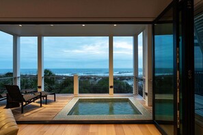 Uma varanda moderna com vista para o oceano, uma piscina pequena e duas cadeiras.