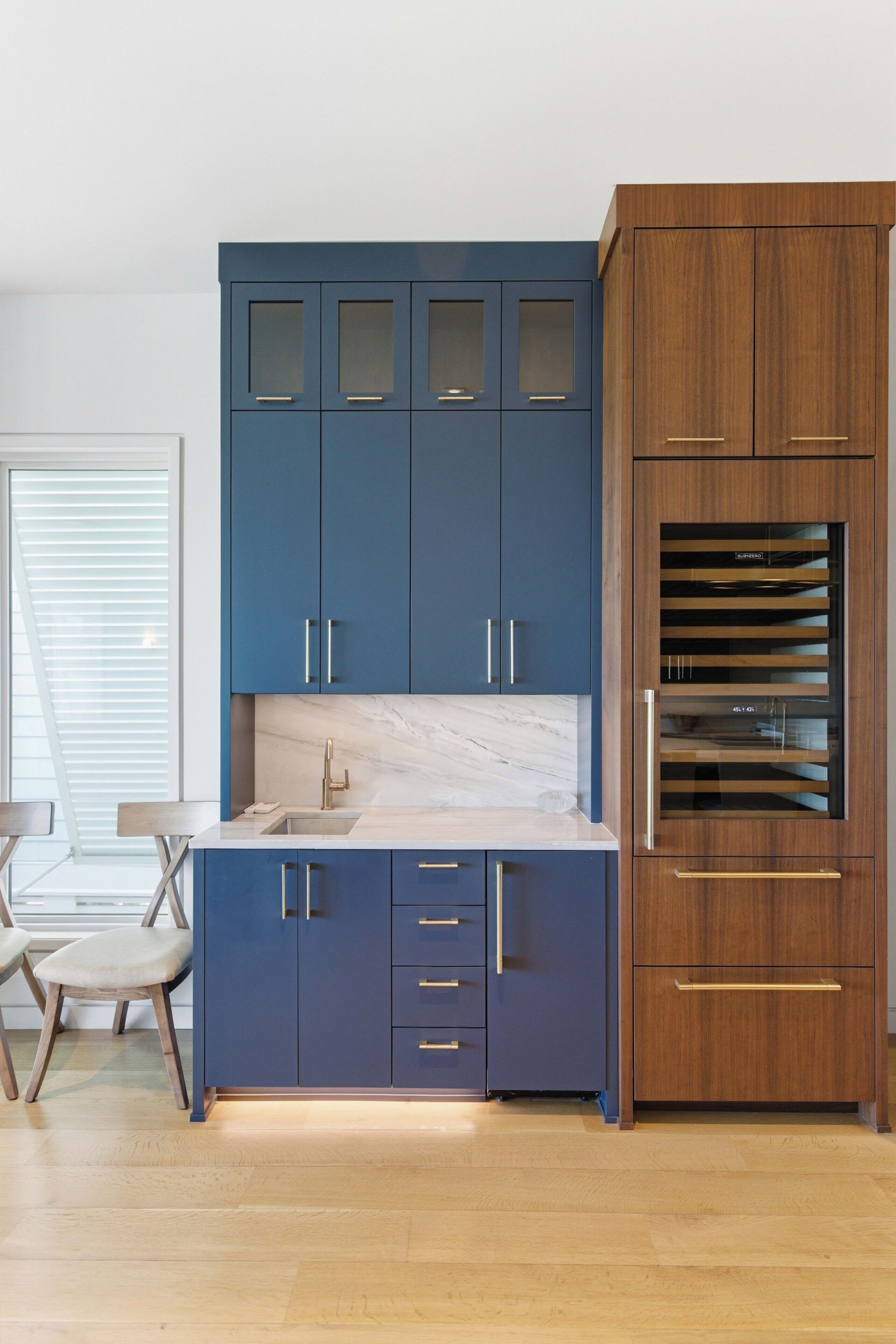 A modern kitchen with blue cabinets, a marble countertop, and a built-in oven.