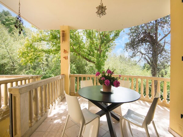 A balcony with a round table and two chairs, a potted plant with flowers, and a decorative hanging light fixture. - Holiday Home in Fano near the Beach (Fano)