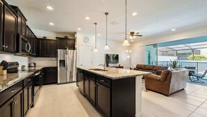 A modern kitchen with dark cabinetry, stainless steel appliances, and a large island. - Family Home w/ Game Loft | Private Pool (Kissimmee)