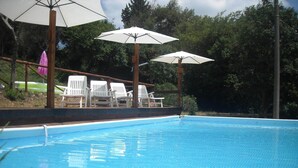 A swimming pool with white lounge chairs and umbrellas.