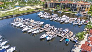 A marina with numerous boats docked, surrounded by a residential area with buildings and palm trees.