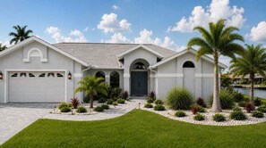 A single-story house with a garage, a front door, and a driveway leading to the entrance. - New listing - Villa Pelican Rose - Gulf access w. heated pool (Cape Coral)