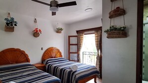 A bedroom with two single beds, a ceiling fan, and a window with curtains. - Hotel Alma de la Sierra (Jonotla)