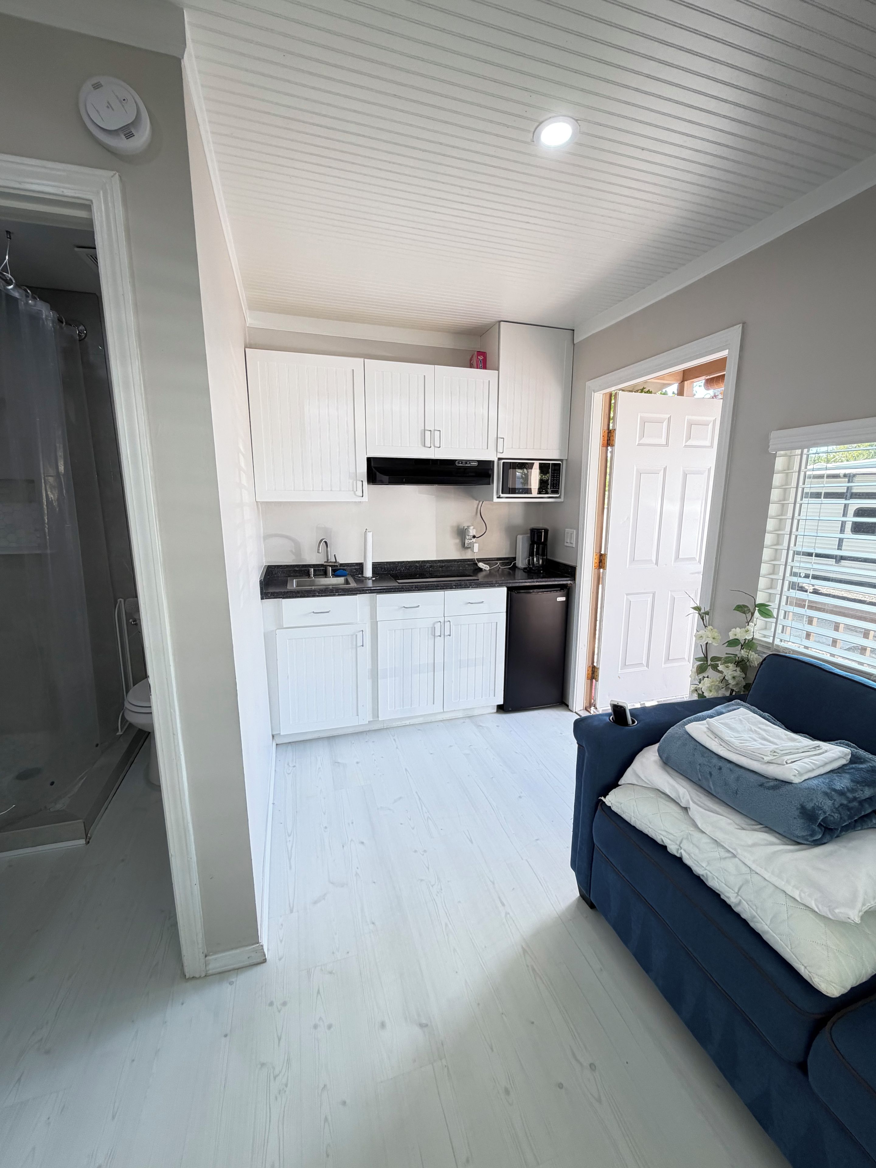 Un espacio habitable compacto con kitchenette, zona de ducha y sofá.