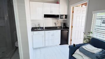 Un espacio habitable compacto con kitchenette, zona de ducha y sofá.