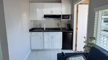 Une cuisine de taille réduite avec des meubles blancs, un plan de travail noir et un four à micro-ondes.