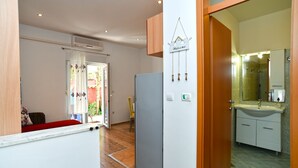 A compact living space with a kitchenette, a refrigerator, a bathroom with a mirror and sink, and a door leading to an outdoor area.