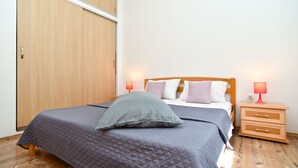 A bedroom with a bed, bedside lamps, a wooden wardrobe, and a nightstand.