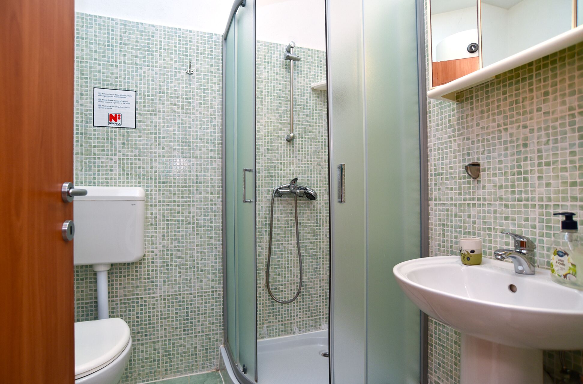 A bathroom with a toilet, a shower with a glass door, and a sink with a mirror above it.