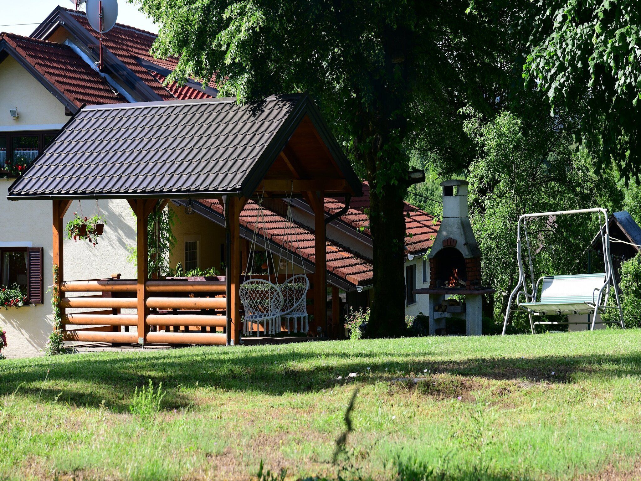 A wooden gazebo with a tiled roof, a brick chimney, and a bench.