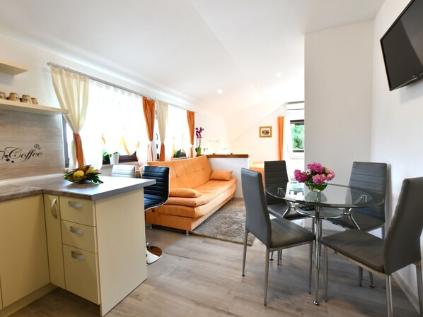 Eine moderne Küche mit Essbereich, einer Couch und einem an der Wand befestigten Fernseher.
