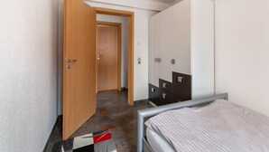Ein Schlafzimmer mit einem Bett, einem Kleiderschrank und einer Tür zu einem anderen Raum.