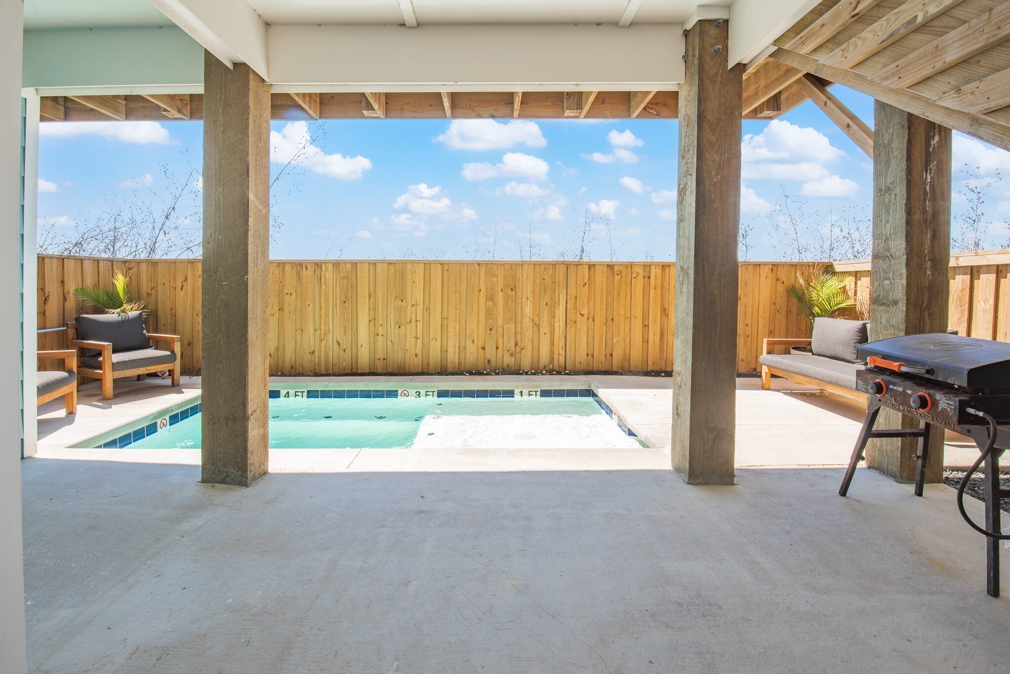 Ein Garten mit Schwimmbad, Holzterrasse und Gartenmöbeln.