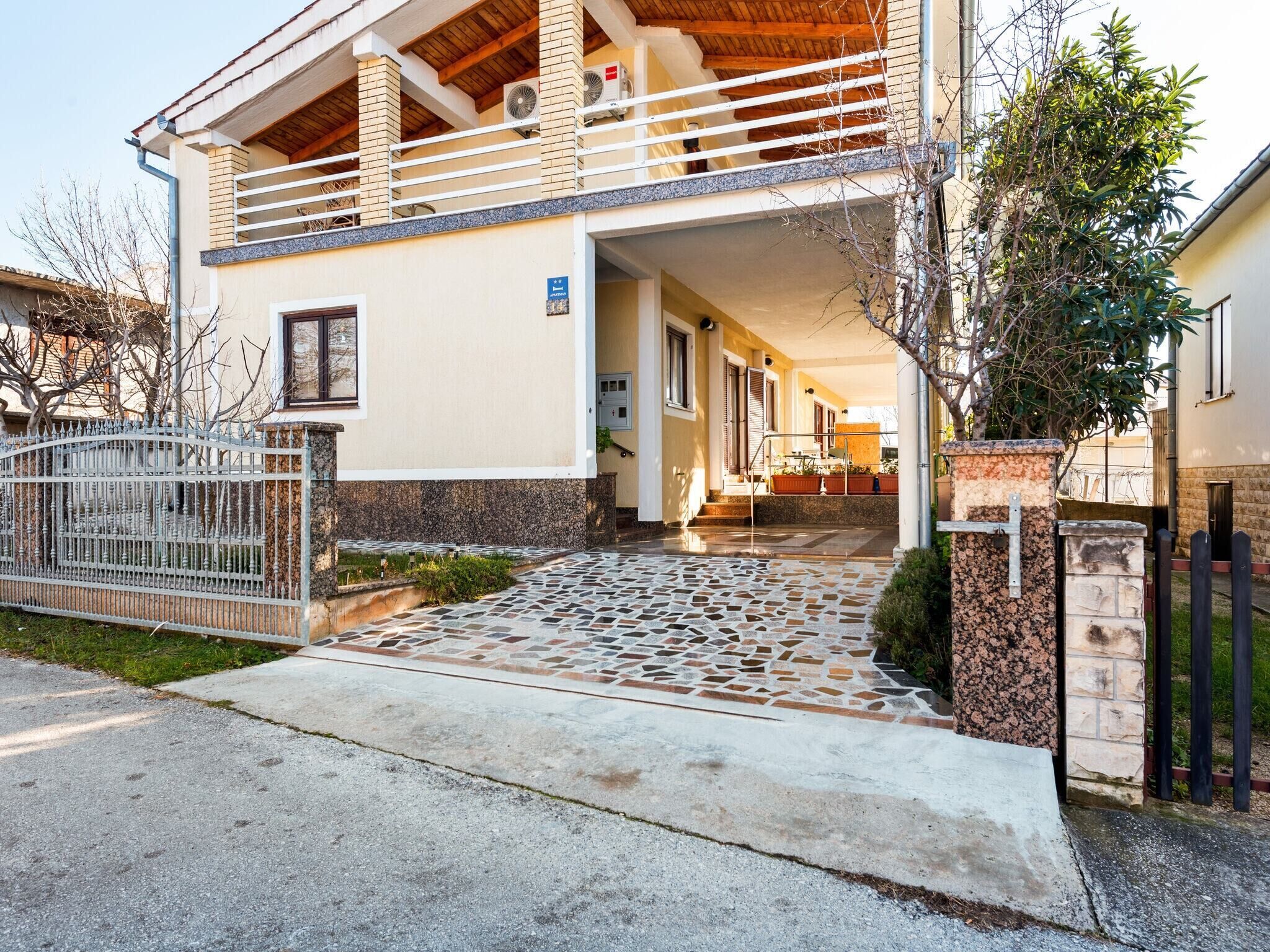 A two-story house with a balcony and a stone-tiled entrance.