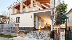 A two-story house with a balcony and a stone-tiled entrance. - Holiday Home in Jasenice near Maslenica Beach (JASENICE)