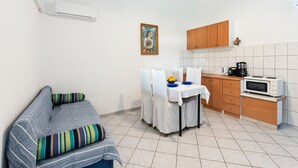 A compact kitchen with a dining table, a sofa with striped cushions, a microwave, and a coffee maker. - Holiday Home in Jasenice near Maslenica Beach (JASENICE)