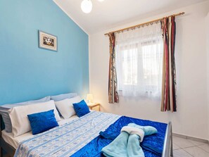 A bedroom with a bed, pillows, a bedside table, a lamp, and a window with curtains. - Holiday Home in Jasenice near Maslenica Beach (JASENICE)