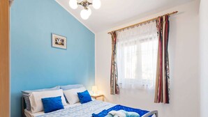 A bedroom with a bed, a bedside table, a lamp, a window with curtains, and a picture on the wall. - Holiday Home in Jasenice near Maslenica Beach (JASENICE)