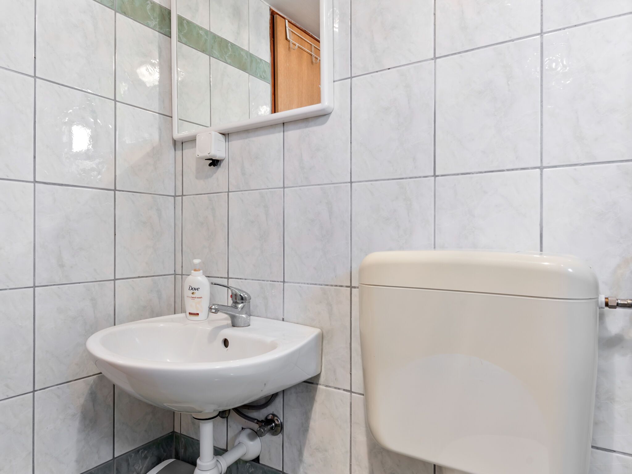 A bathroom with a white sink, a toilet, and a mirror.