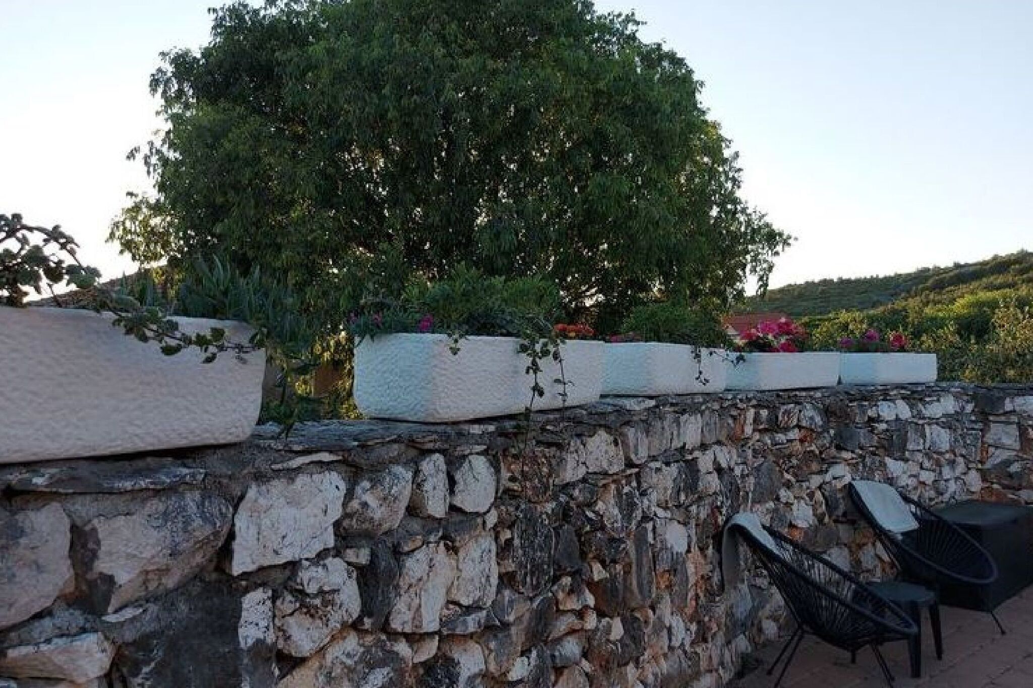 A stone wall with planters and a seating area.