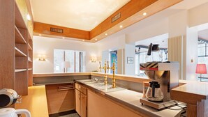 Eine moderne Küche mit integrierter Kaffeemaschine, Spüle und Fenster mit Blick ins Freie.
