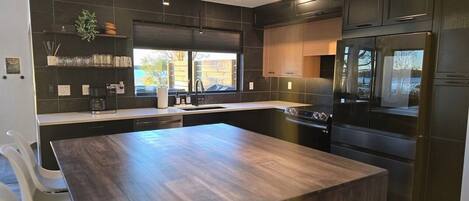 A modern kitchen with dark cabinetry, a central island, and a view of the outdoors.