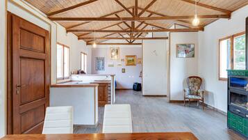 A spacious kitchen with a wooden ceiling, a dining area with a wooden table, and a green appliance.