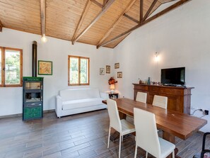 A room with a wooden ceiling, a white sofa, a dining table with chairs, a television, and a fireplace. - Holiday Home in Tuscany with Private Garden (Pieve Santo Stefano (AR))
